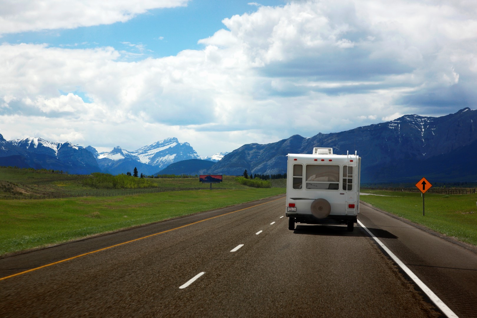 Rear view of a small RV being towed down a highway.