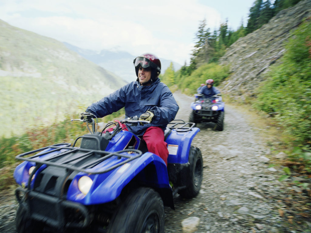 Man driving ATV with group on mountain road