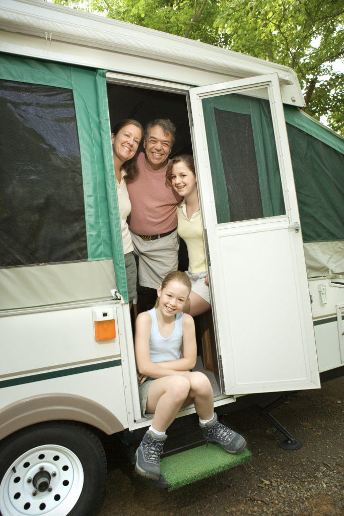 Smiling family in the doorway of a small RV.