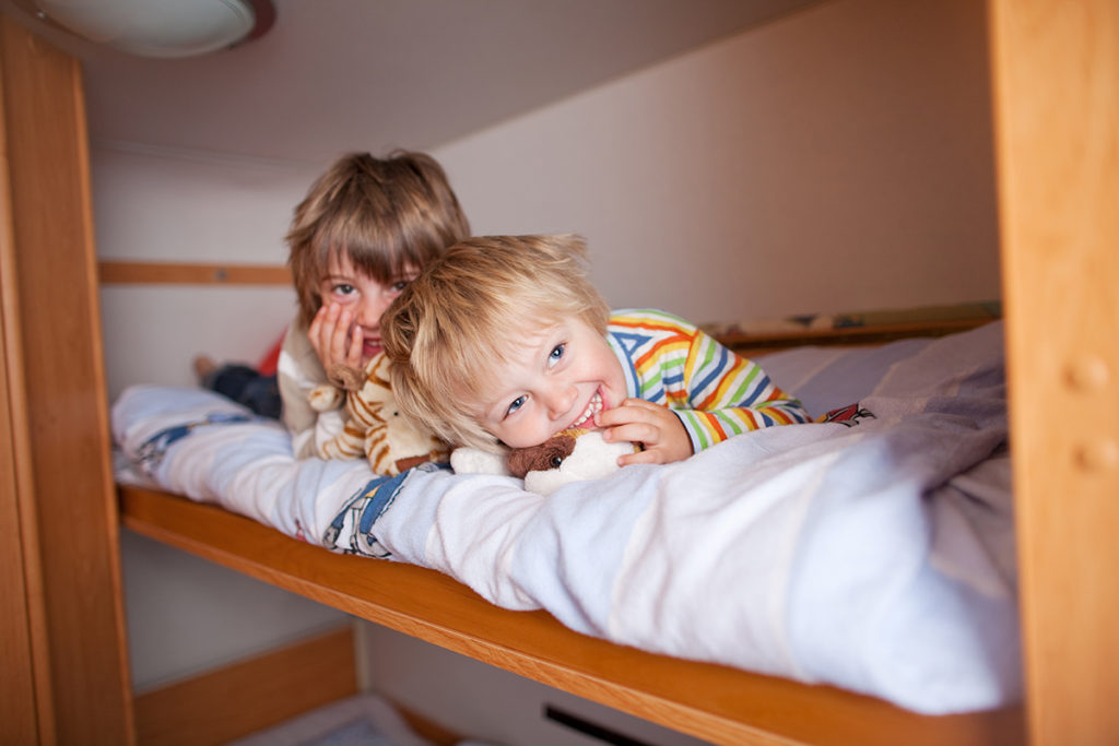 Two smiling young boys enjoying the top bunk in a bunkhouse trailer