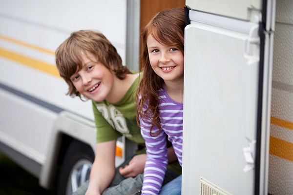 Brother and sister sitting in the doorway of an RV guest house.