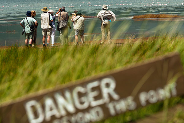 A group of campers taking pictures beyond a warning sign.