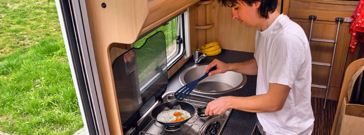 A man cooking in an RV using propane heat